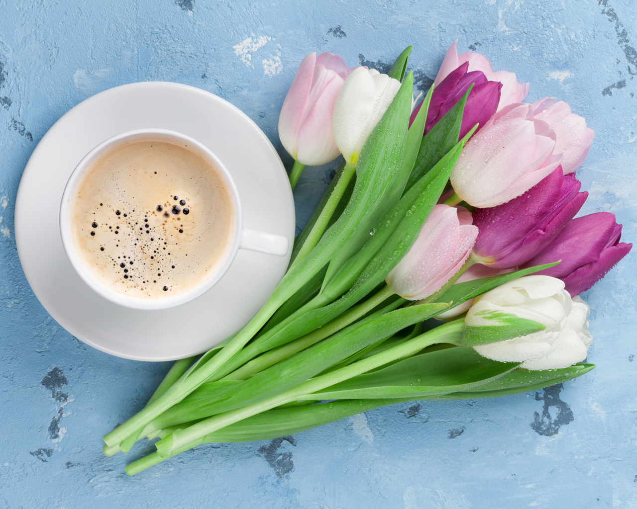 Букет разноцветных тюльпанов с чашкой кофе на голубом столе