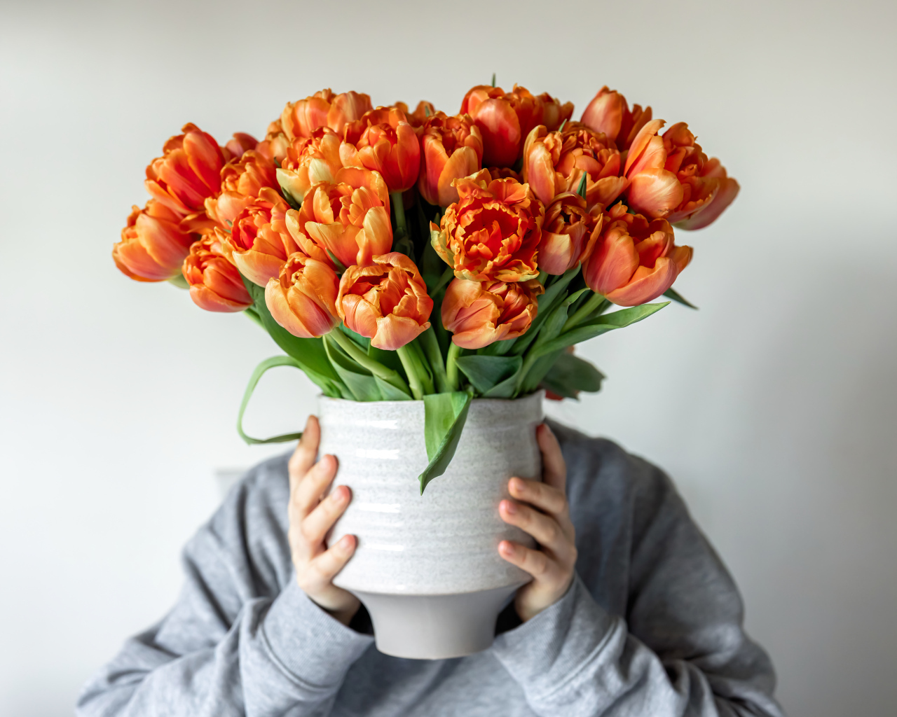Букет оранжевых тюльпанов в вазе в руках