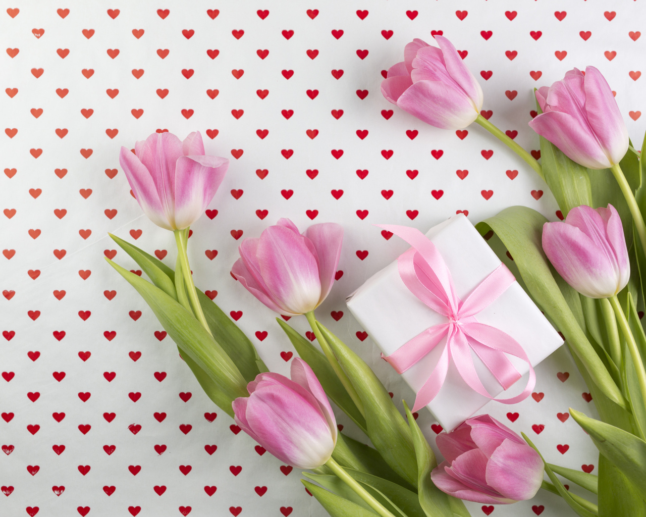 Букет розовых тюльпанов и подарок на фоне с сердечками