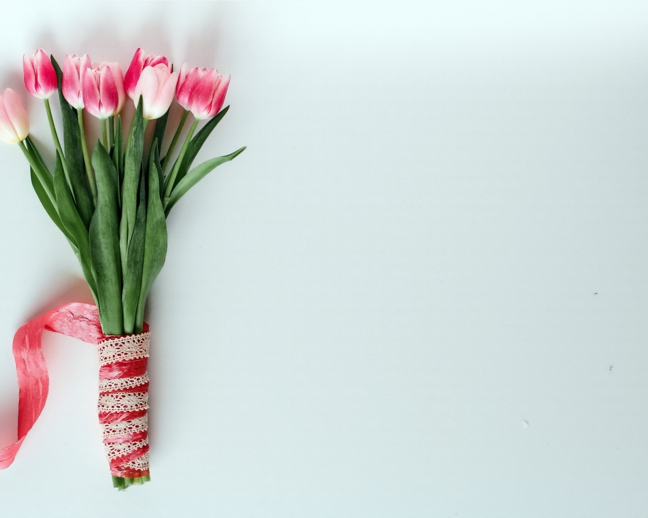 Букет розовых тюльпанов с атласной лентой на сером фоне