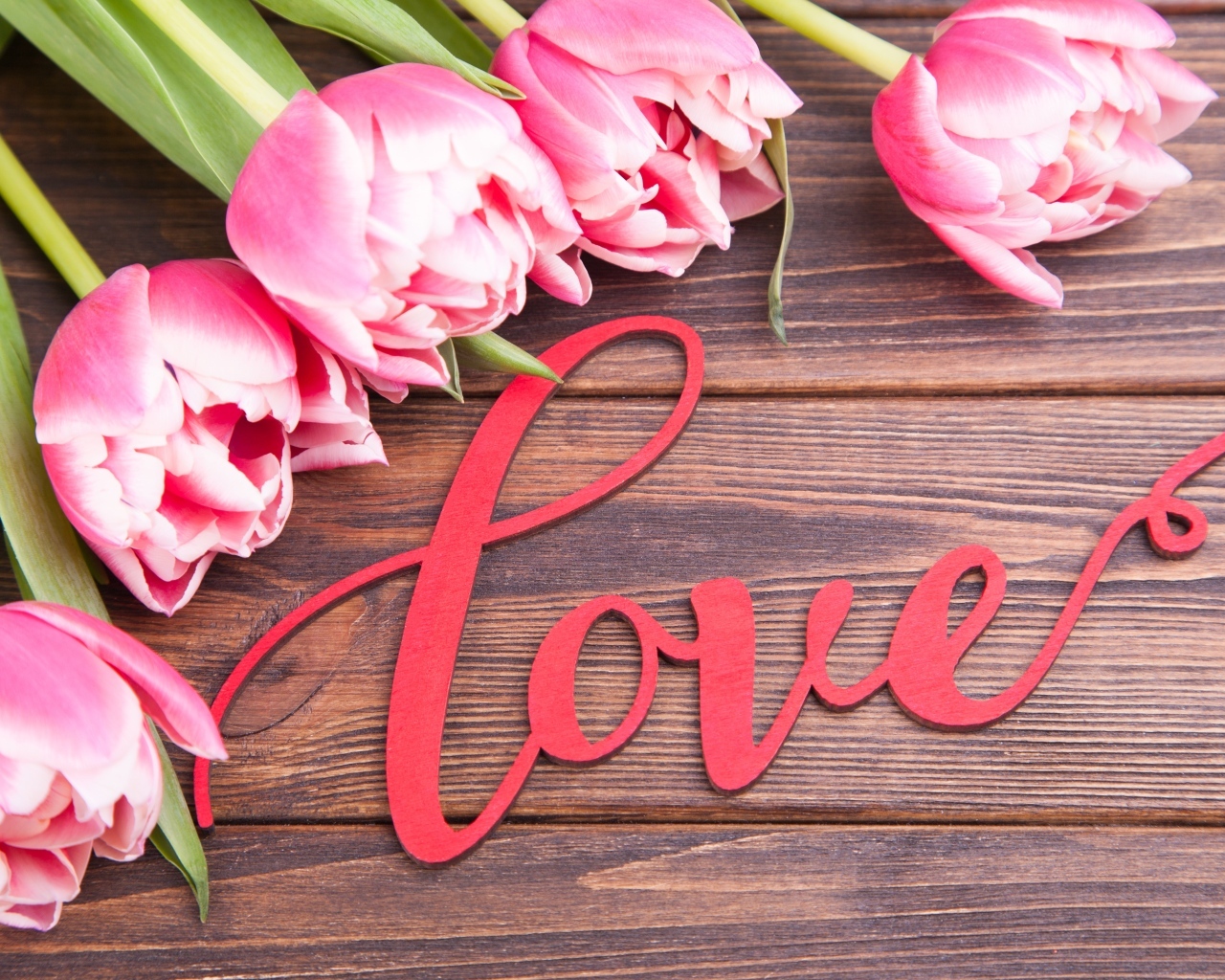 Букет розовых тюльпанов с надписью любовь на деревянном столе