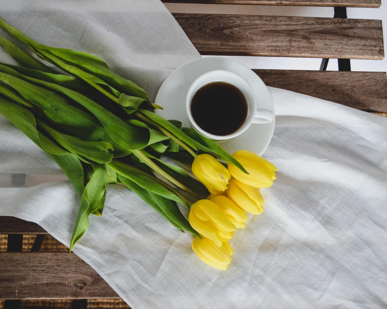 Букет желтых тюльпанов с чашкой кофе на лавке