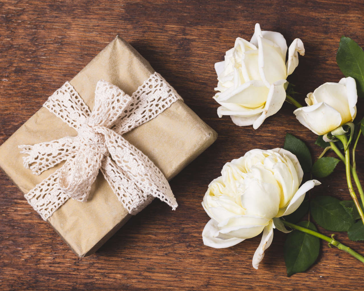 Коробка с подарком на деревянном столе с белыми розами