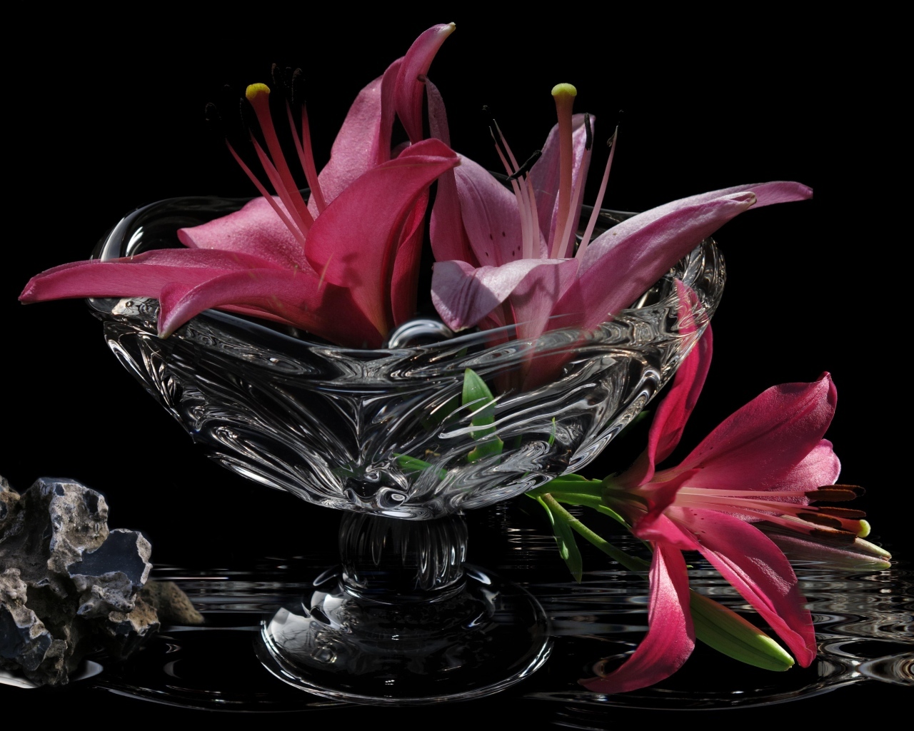 Розовые лилии в стеклянной вазе на столе