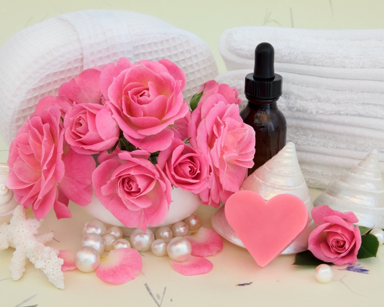 Розовые розы с полотенцами, ракушками и маслом на столе