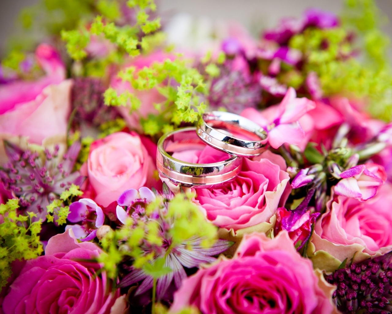 Два обручальных кольцо на букете розовых цветов