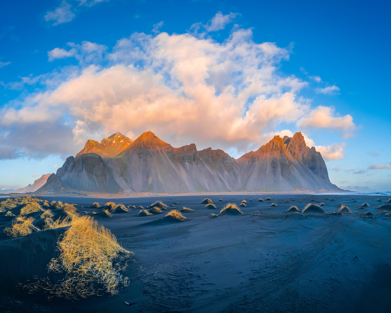 Облако в голубом небе над покрытой солнцем горой