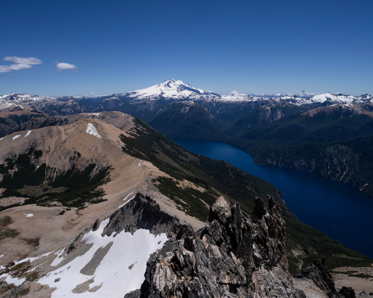 Высокие заснеженные горы и река под голубым небом