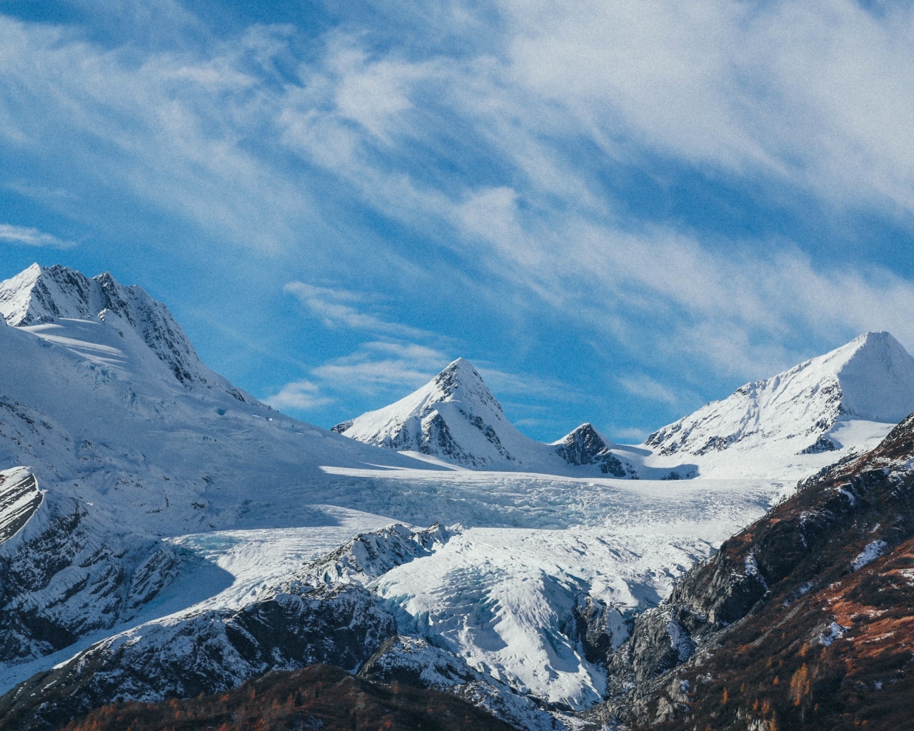 Высокие заснеженные горы под голубым ясным небом