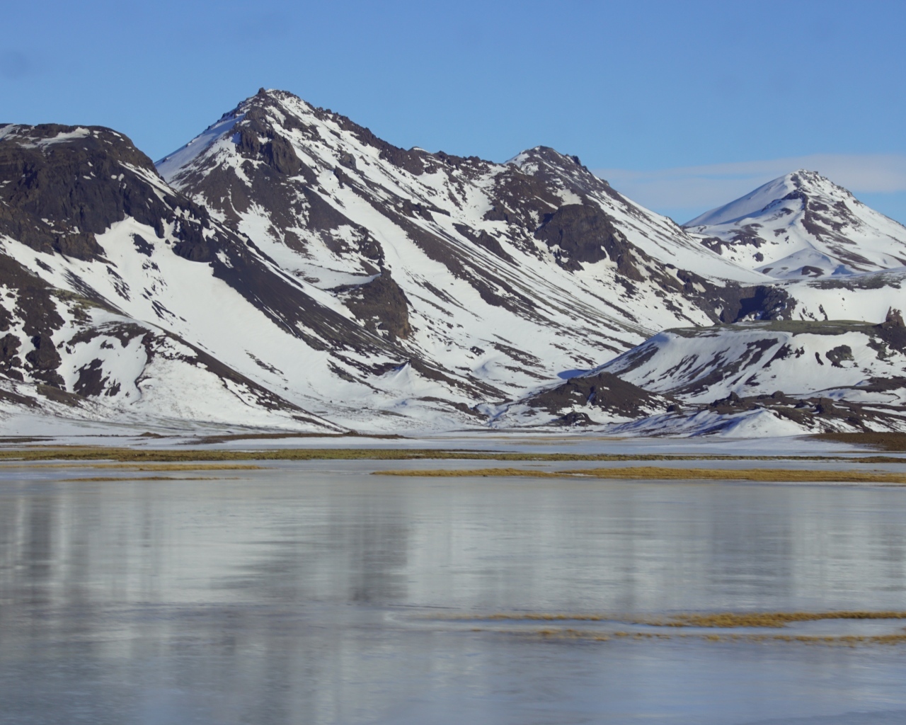 Горы в снегу под голубым небом у воды