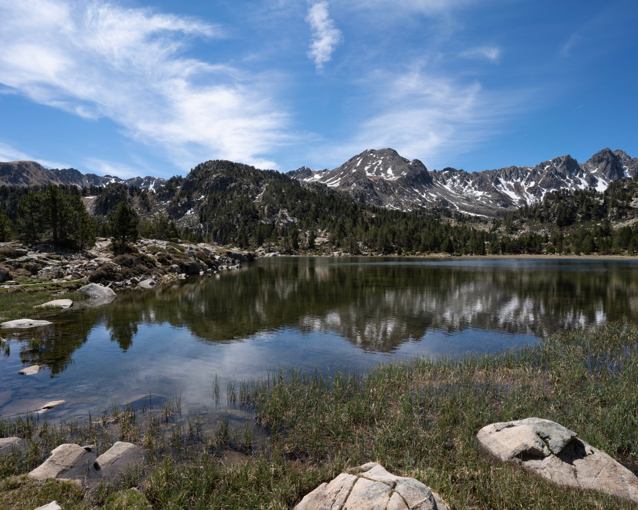 Горы отражаются в воде озера с большими камнями