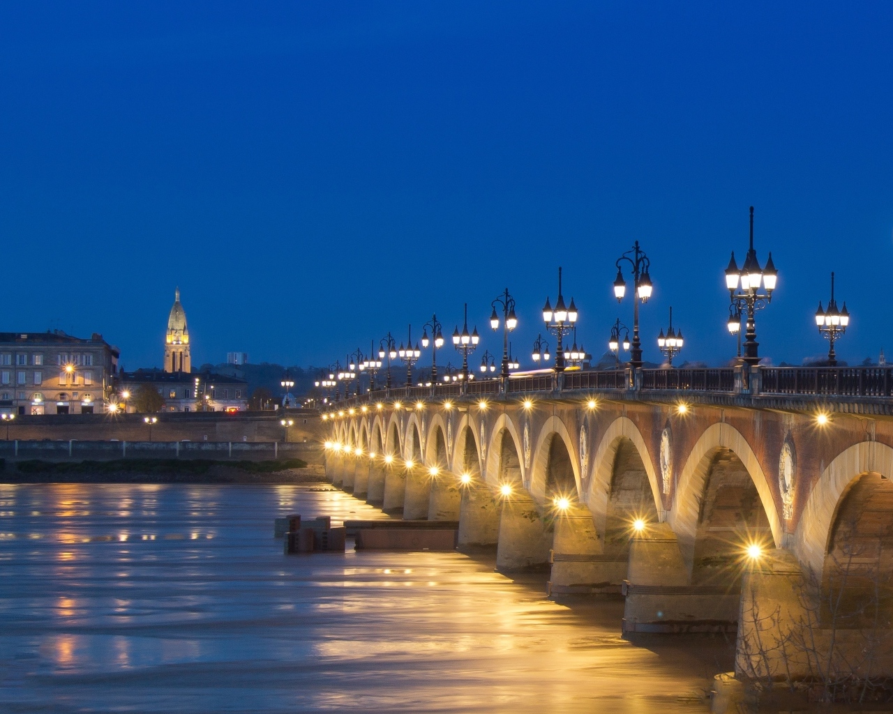 Красивый светящийся мост через реку ночью 