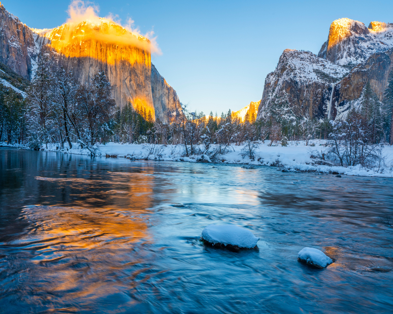 Холодная река с заснеженными берегами и горы в лучах солнца