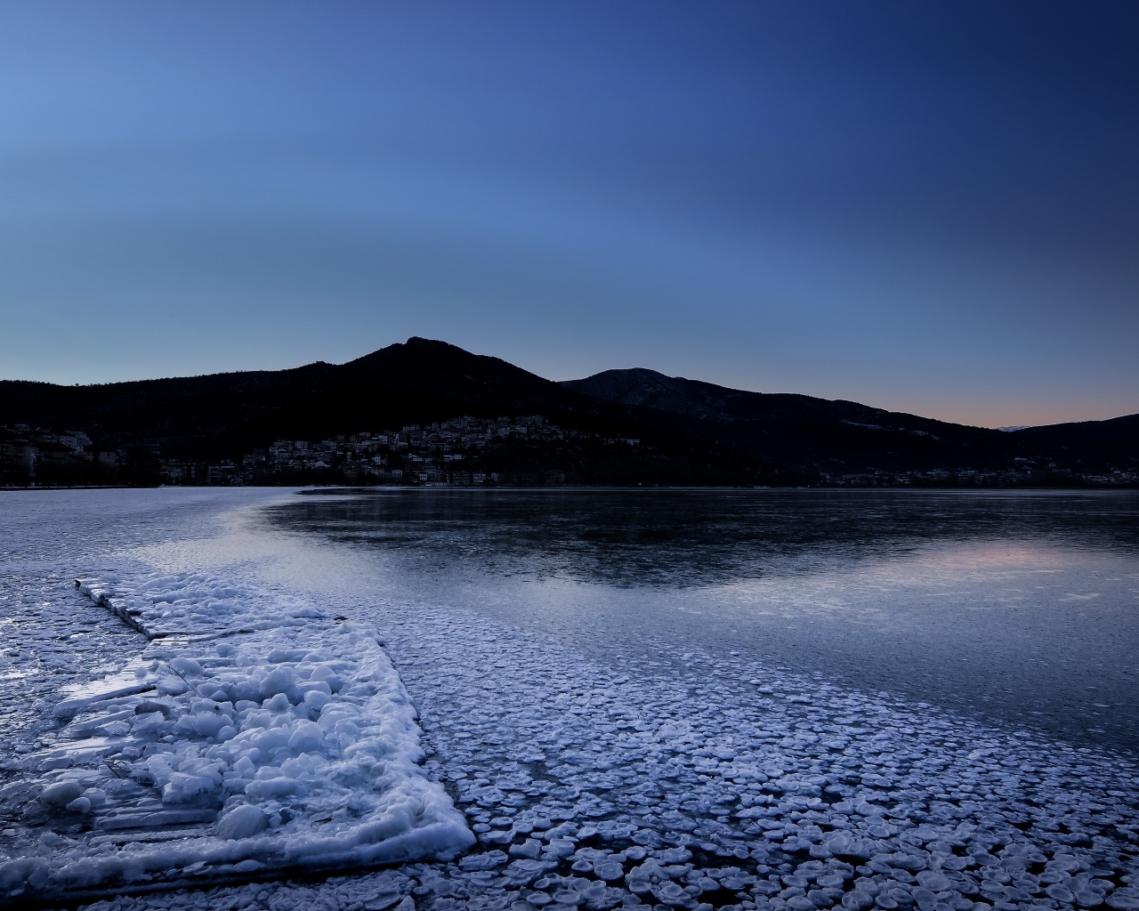 Заледеневшая вода в горном озере в сумерках