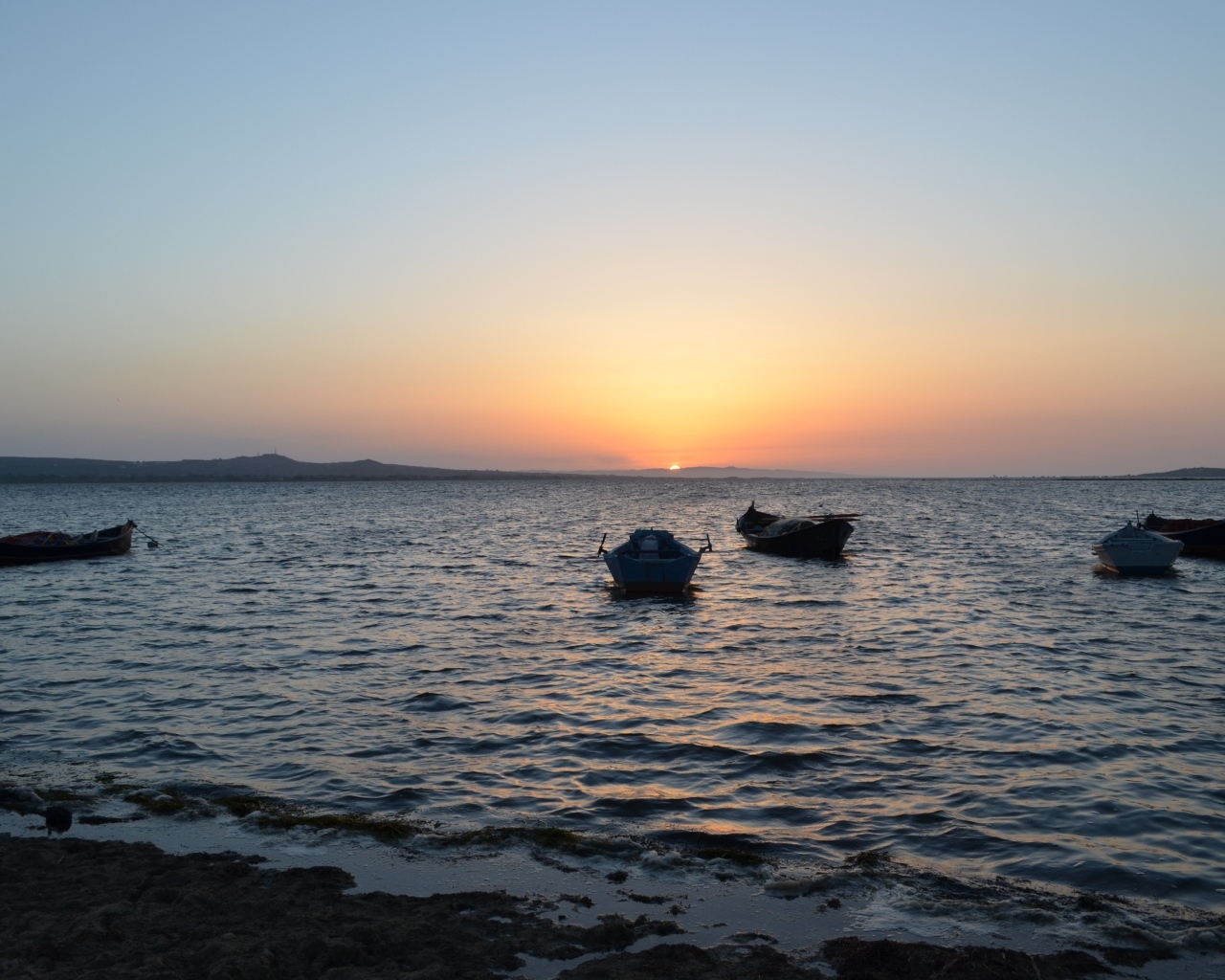 Лодки на морском побережье на закате