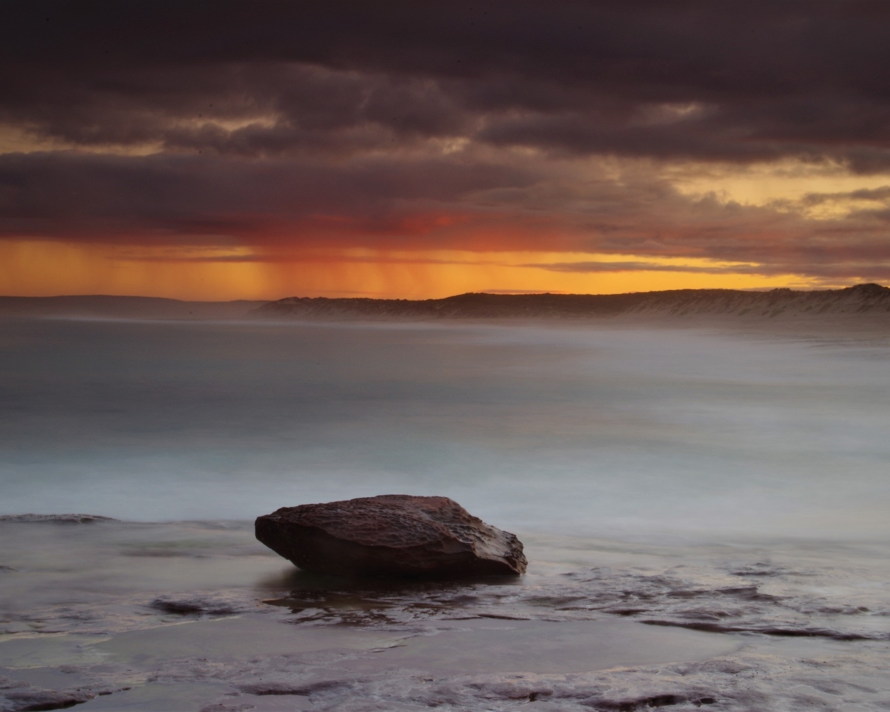 Большой камень в воде на фоне грозового неба в море
