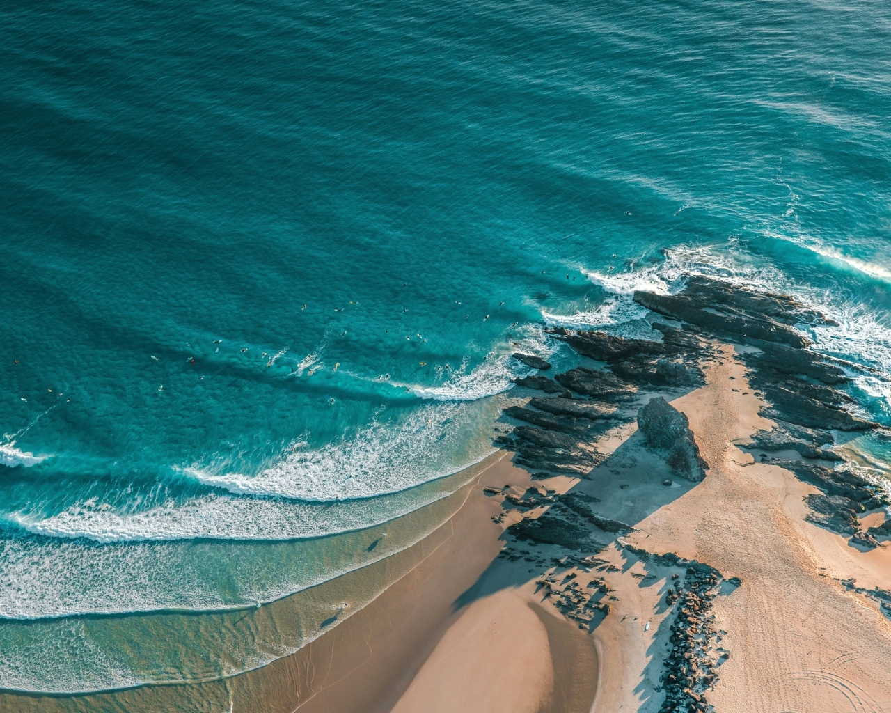 Песчаный берег с большими камнями у океана