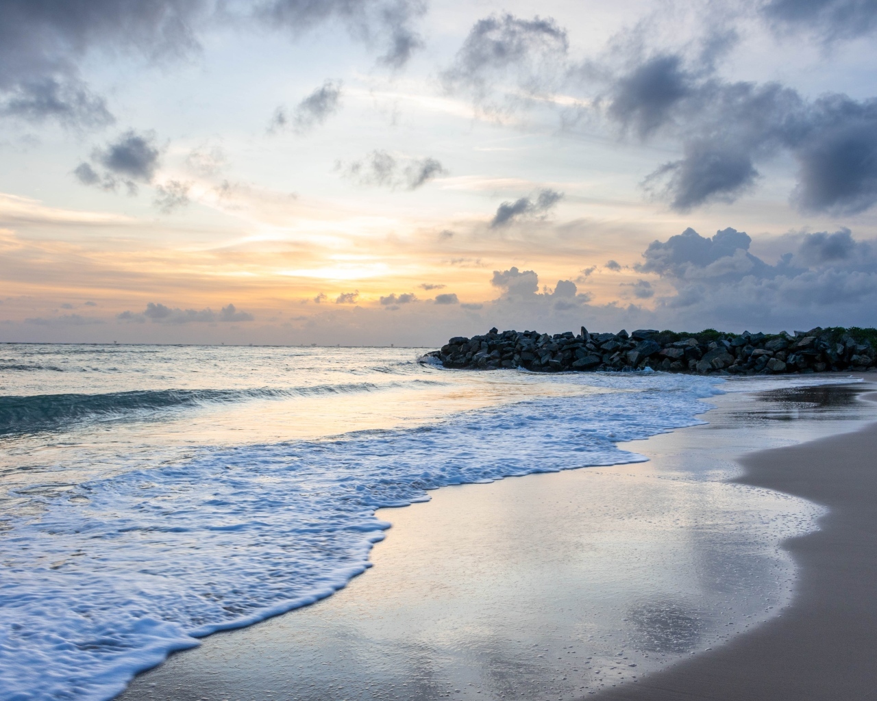 Волны омывают морской песок на рассвете