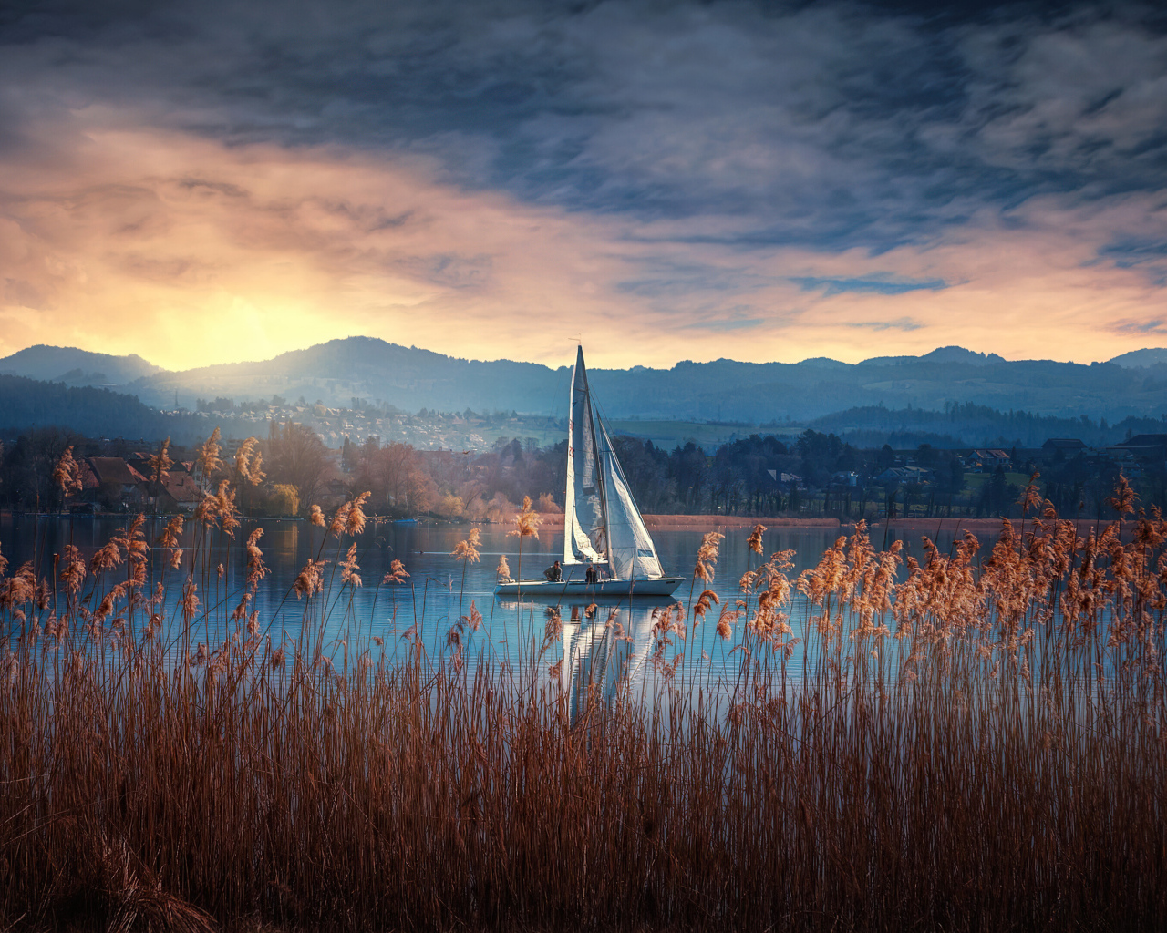 Парусная лодка на озере на закате солнца