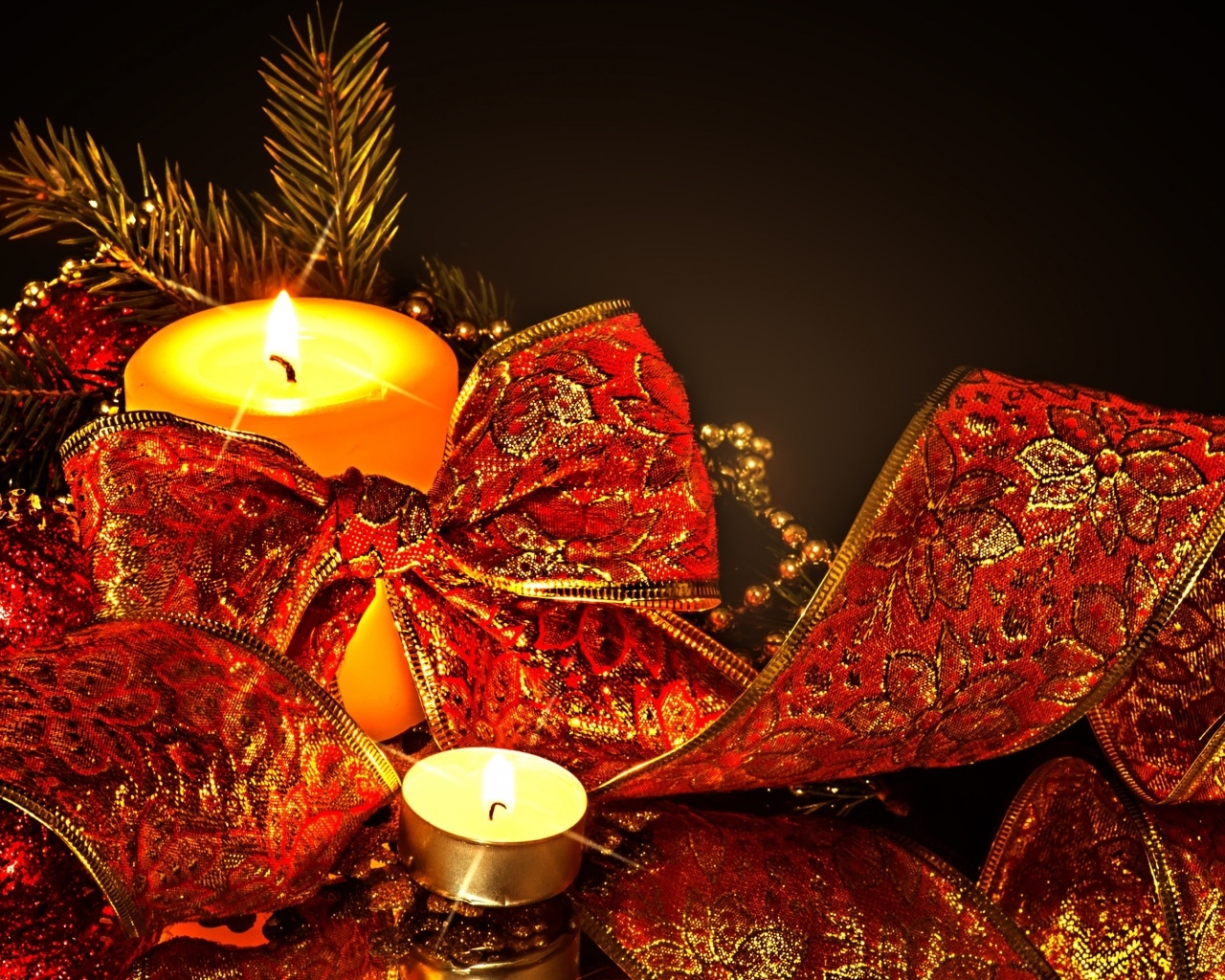 Зажженная свеча с красным бантом на черном фоне на Новый год