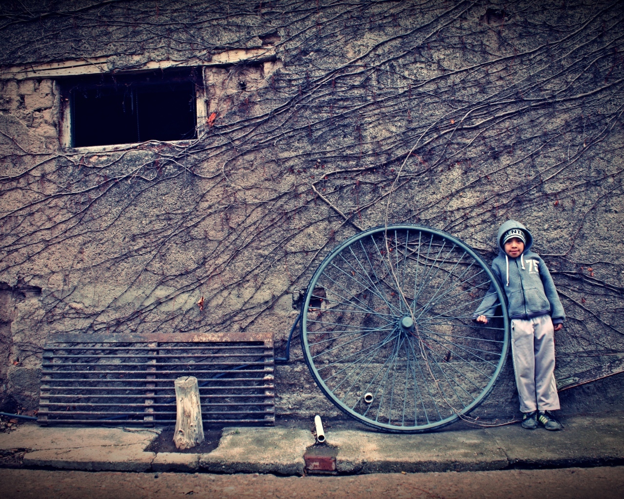 Мальчик с большим колесом стоит у стены