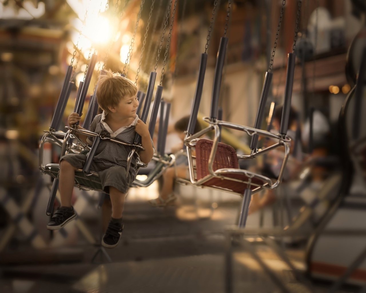Маленький мальчик катается на каруселях