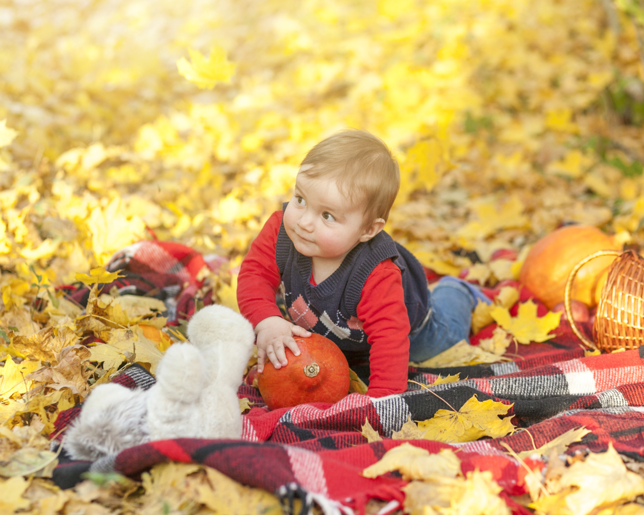 Маленький ребенок лежит на покрывале на земле осенью