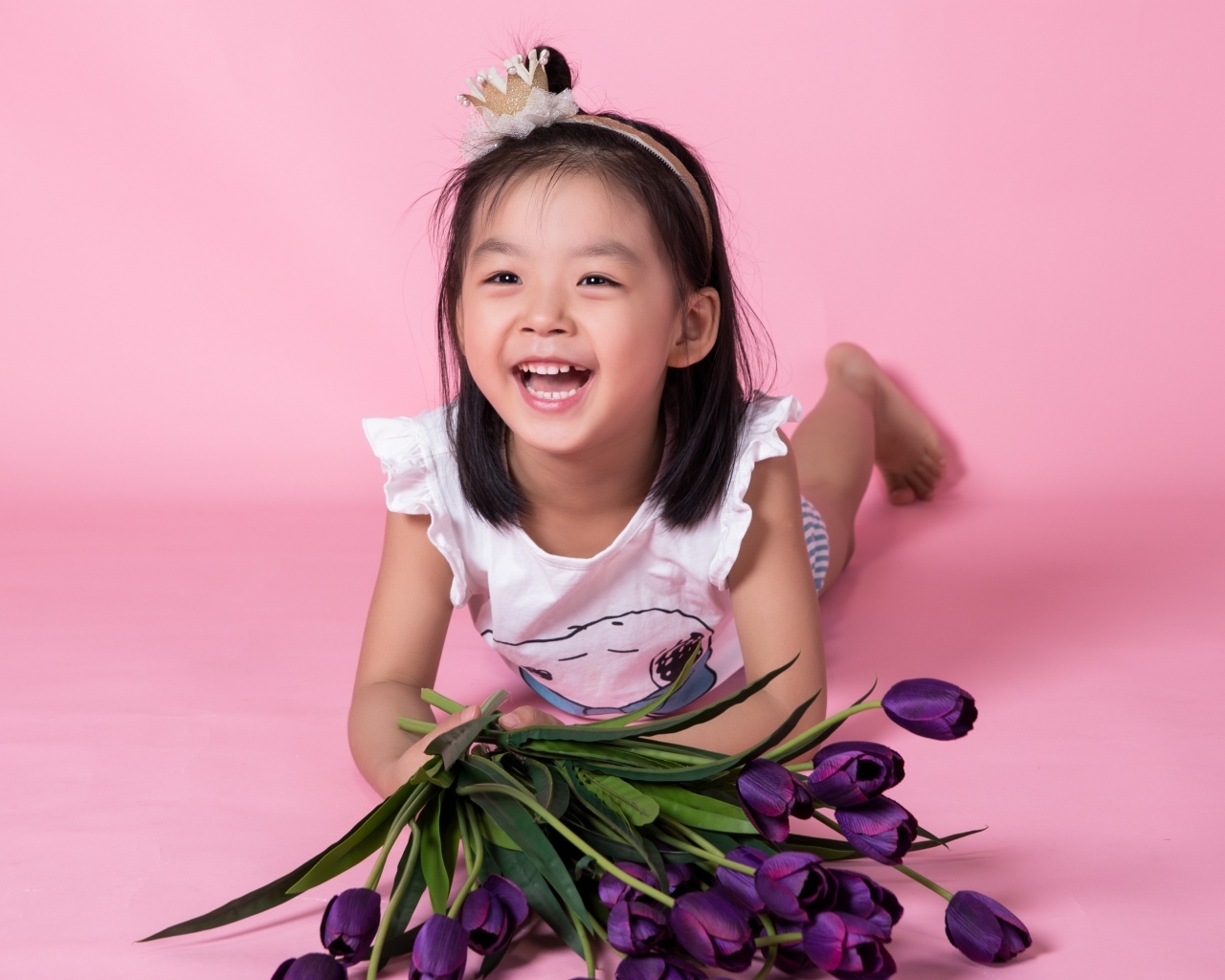 Девочка азиатка в букетом тюльпанов на розовом фоне