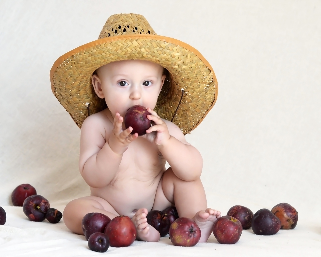 Малыш в шляпе грызет яблоки
