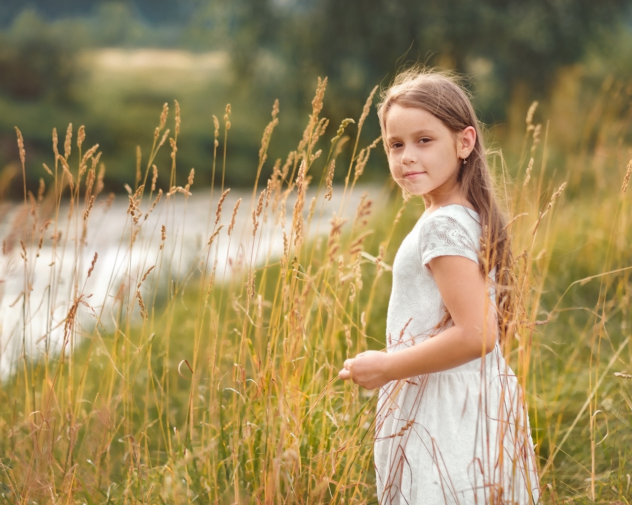 Красивая девочка в белом платье гуляет по траве