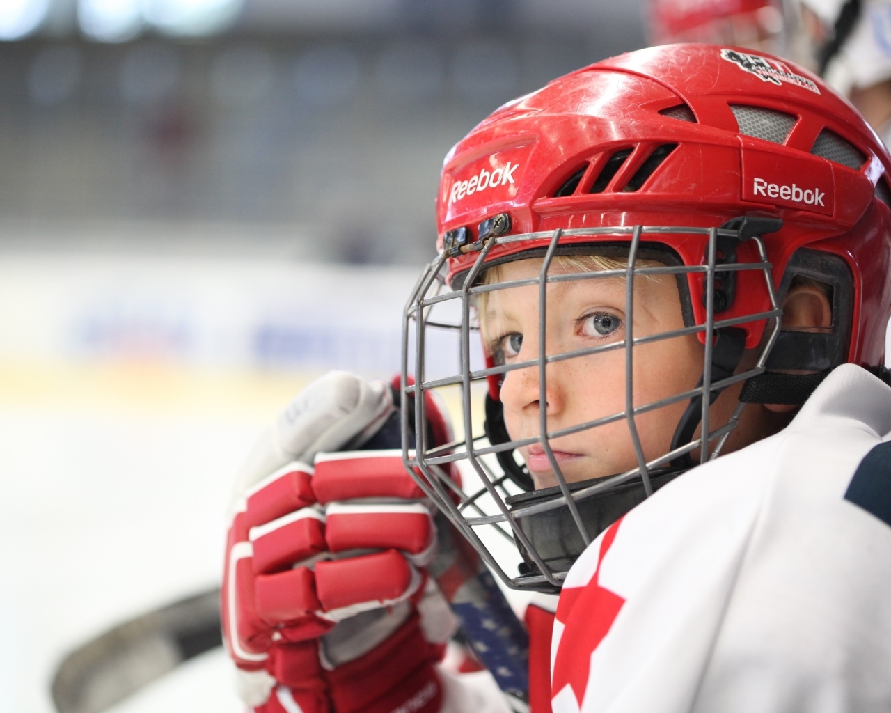 Мальчик в красном шлеме хоккеиста на поле