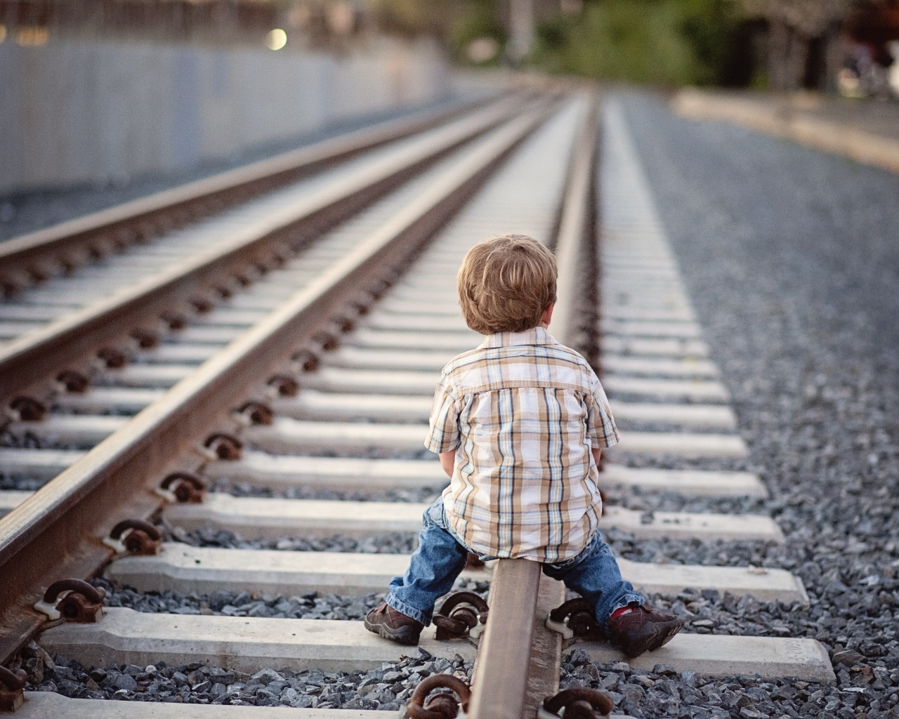 Мальчик сидит на железнодорожных рельсах