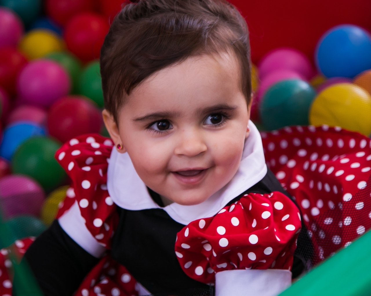 Кареглазая девочка в бассейне с шариками