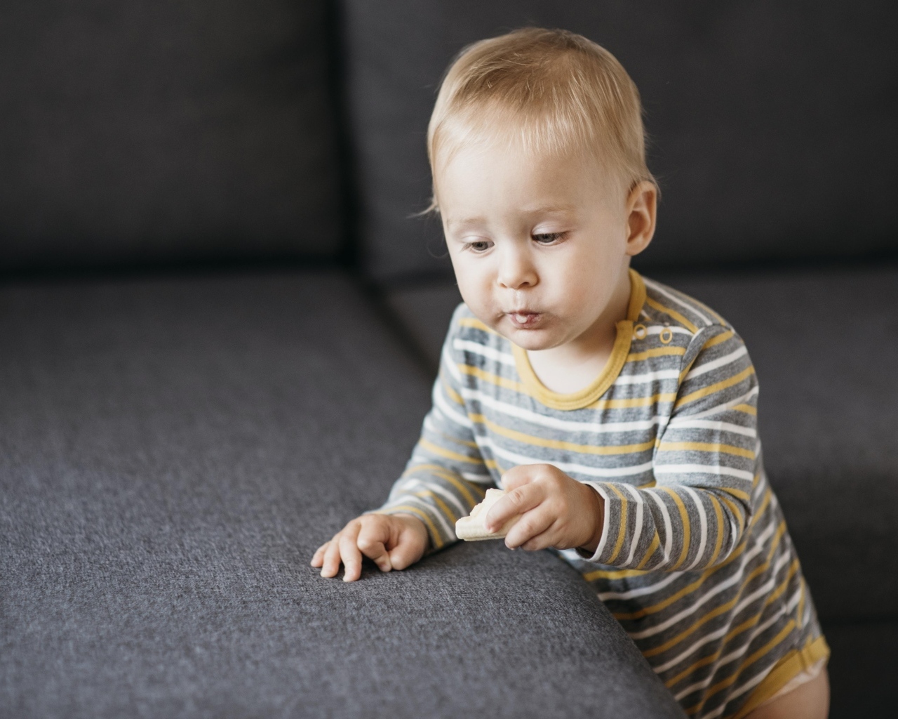 Любопытный маленький ребенок у дивана