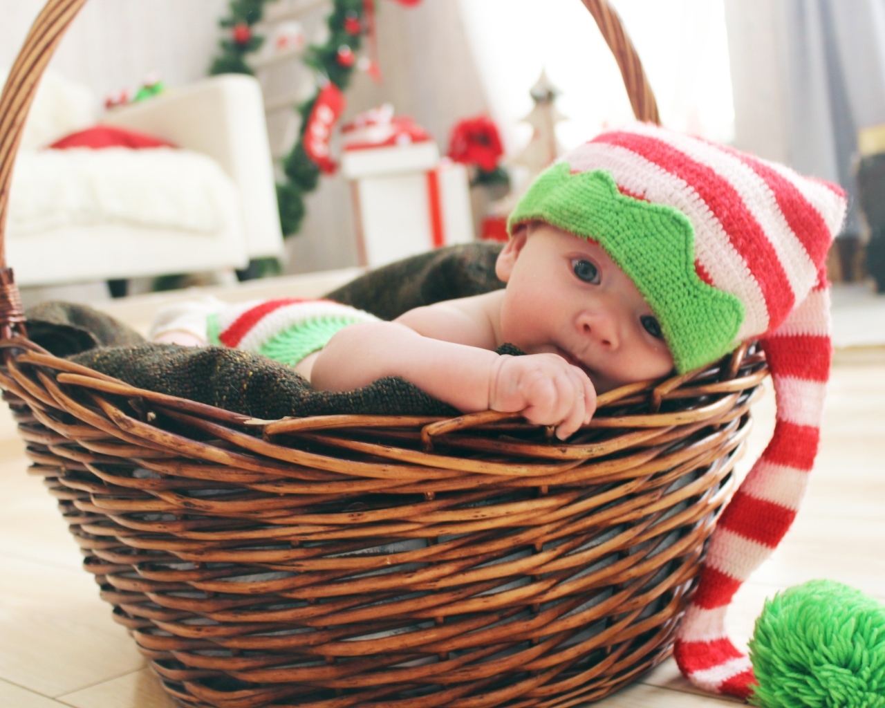 Милый малыш в большой вязаной шапке в корзине