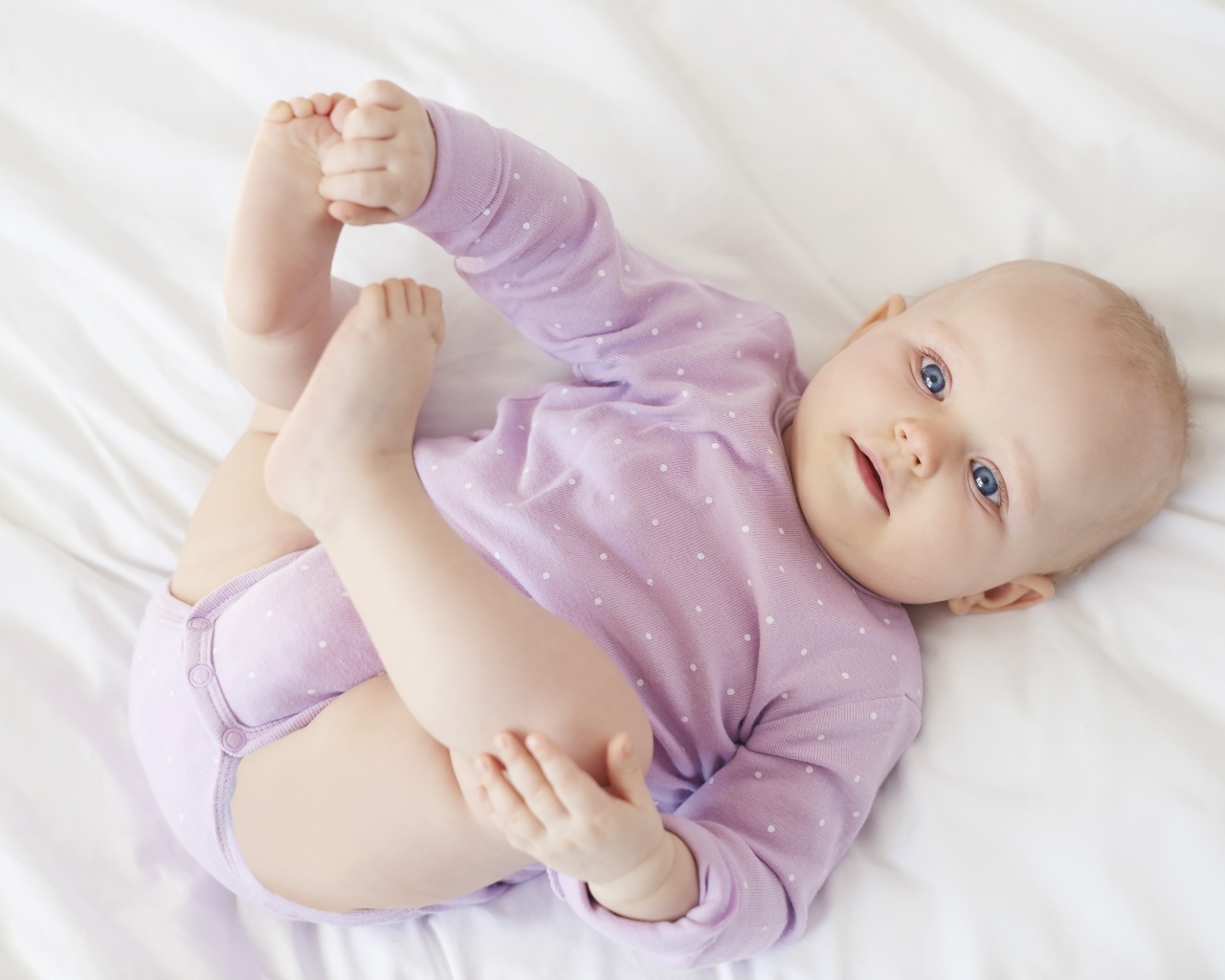 Милый голубоглазый малыш на белом покрывале