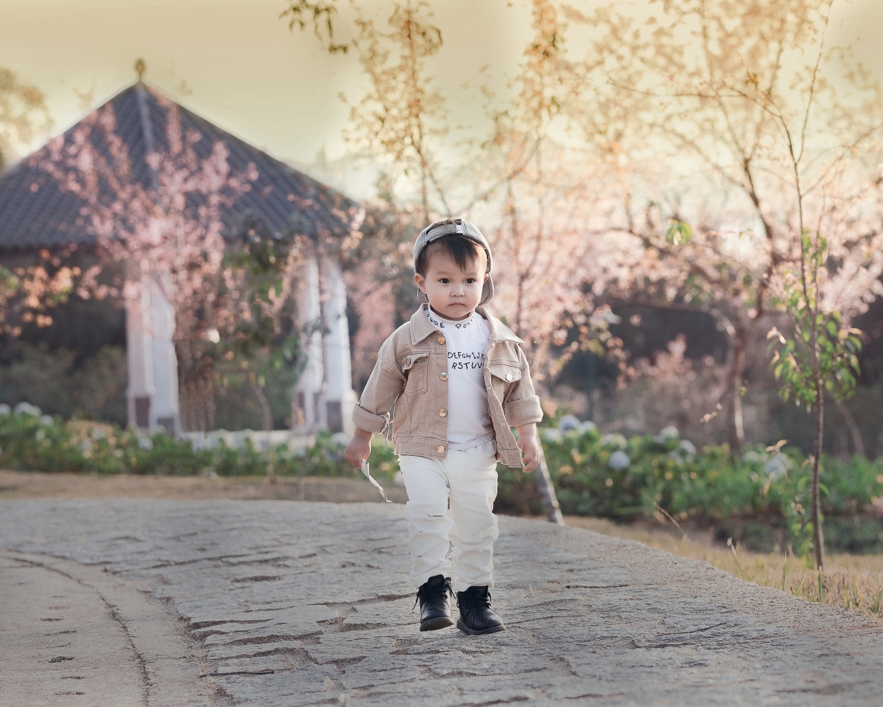 Милый мальчик гуляет по дороге у дома