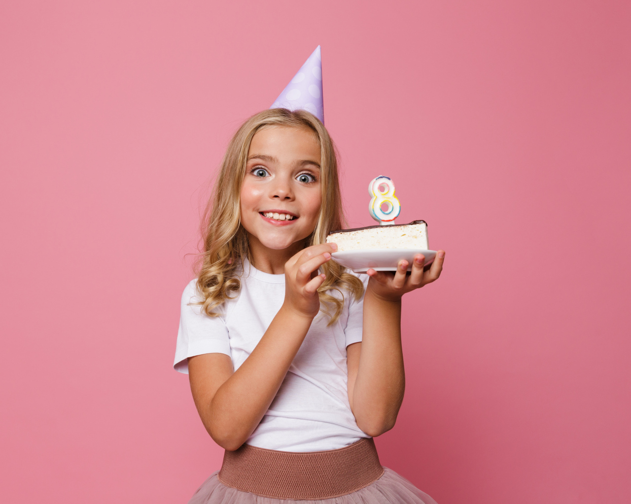 Милая девочка отмечает день рождения на розовом фоне