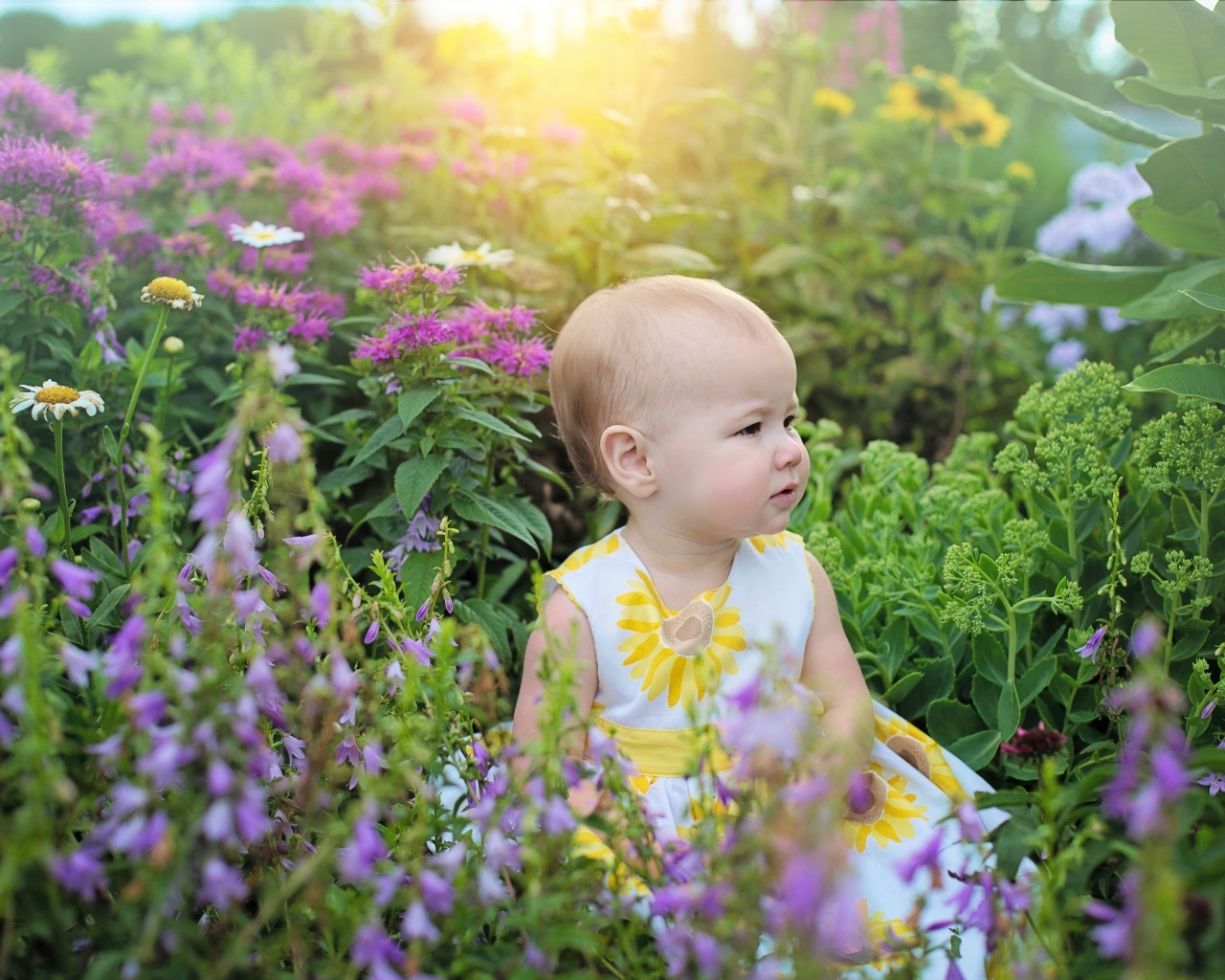 Милая девочка в платье сидит в цветах
