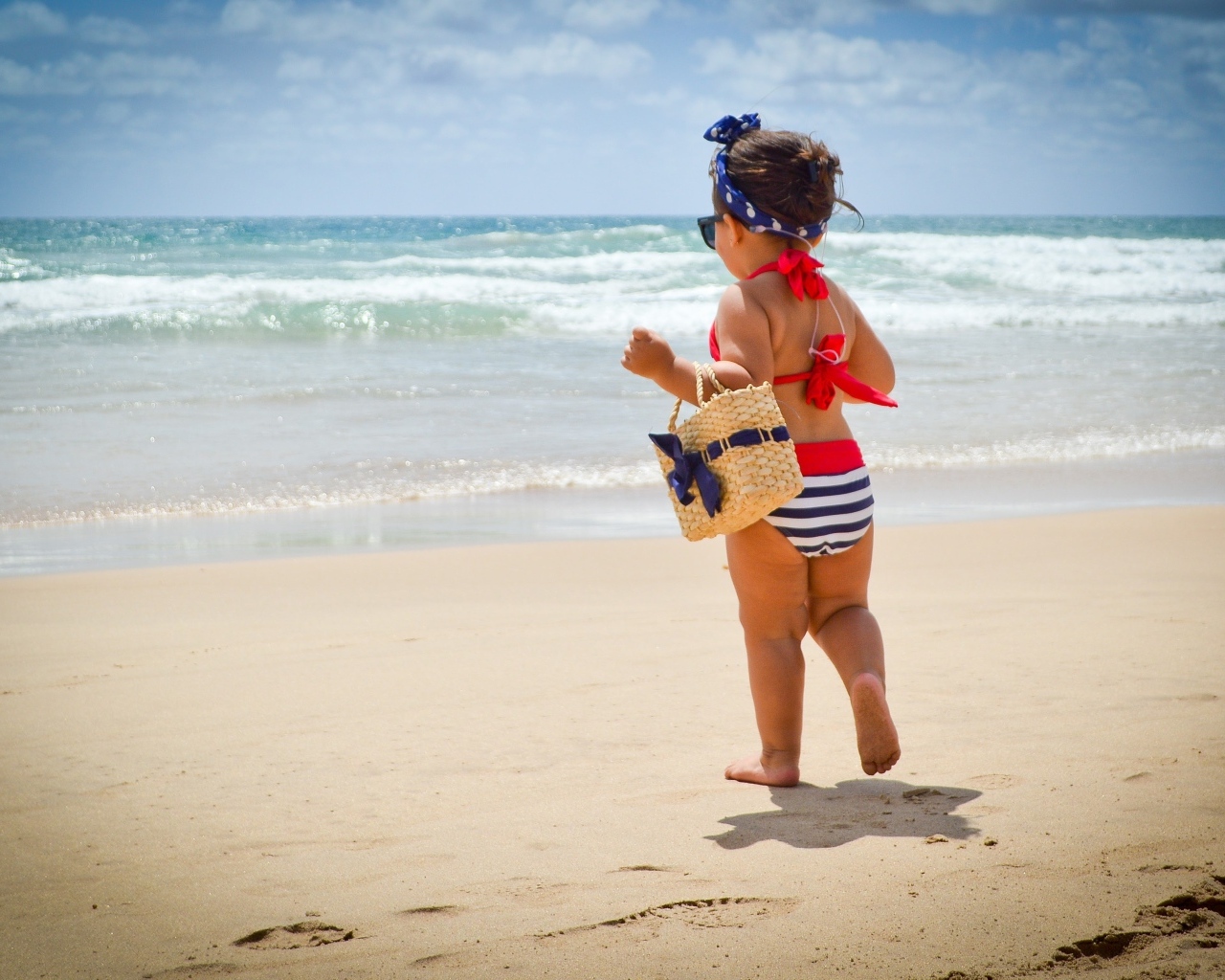 Модная маленькая девочка с сумочкой на берегу моря