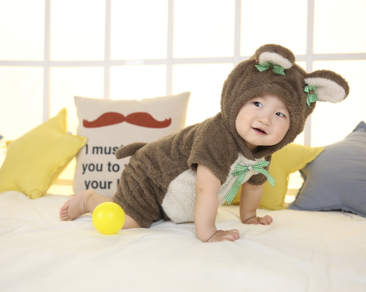 Смешной ребенок азиат в костюме на кровати