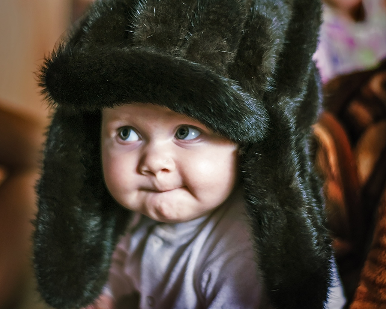 Смешной ребенок в черной меховой шапке