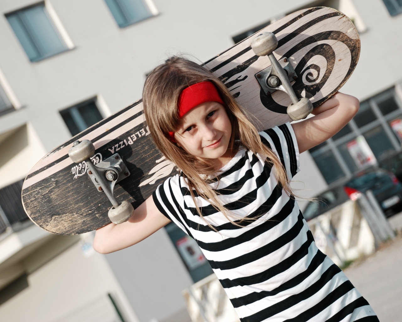 Девочка в полосатом платье со скейтбордом в руках