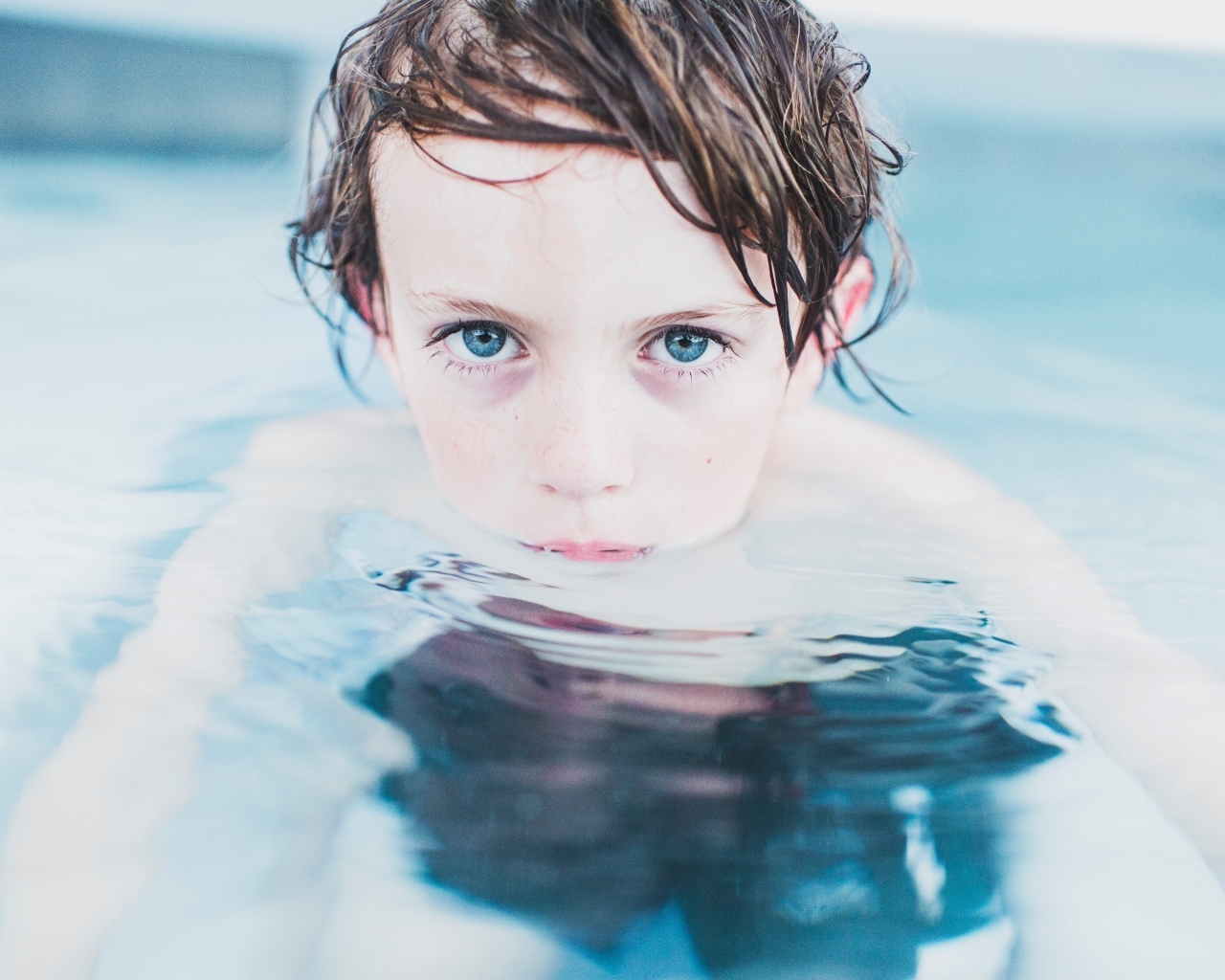 Маленький голубоглазый мальчик в бассейне