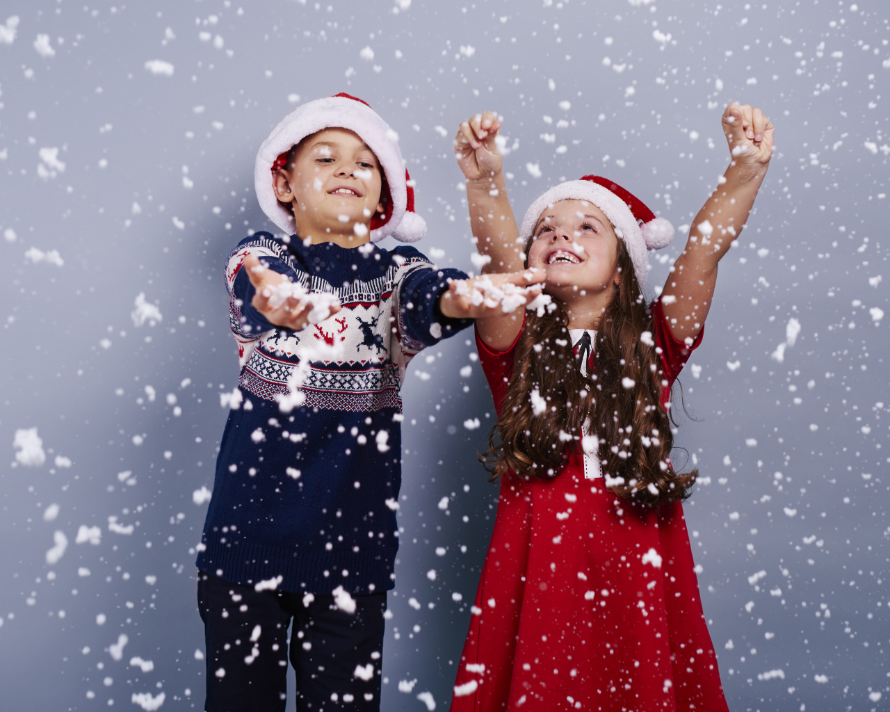 Маленькие мальчик и девочка ловят снег