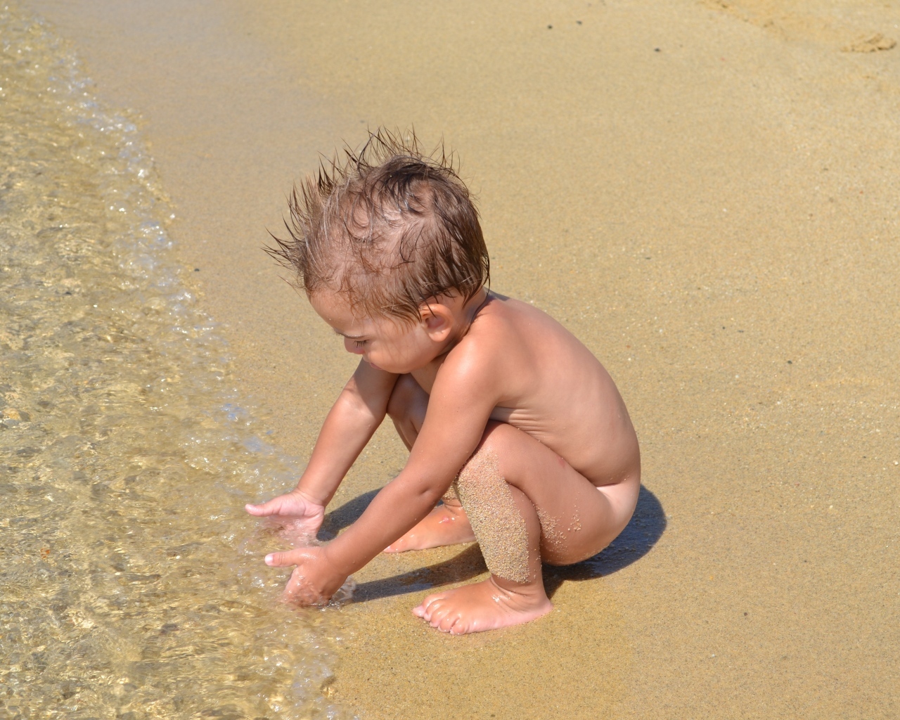 Маленький мальчик на пляже у моря на песке