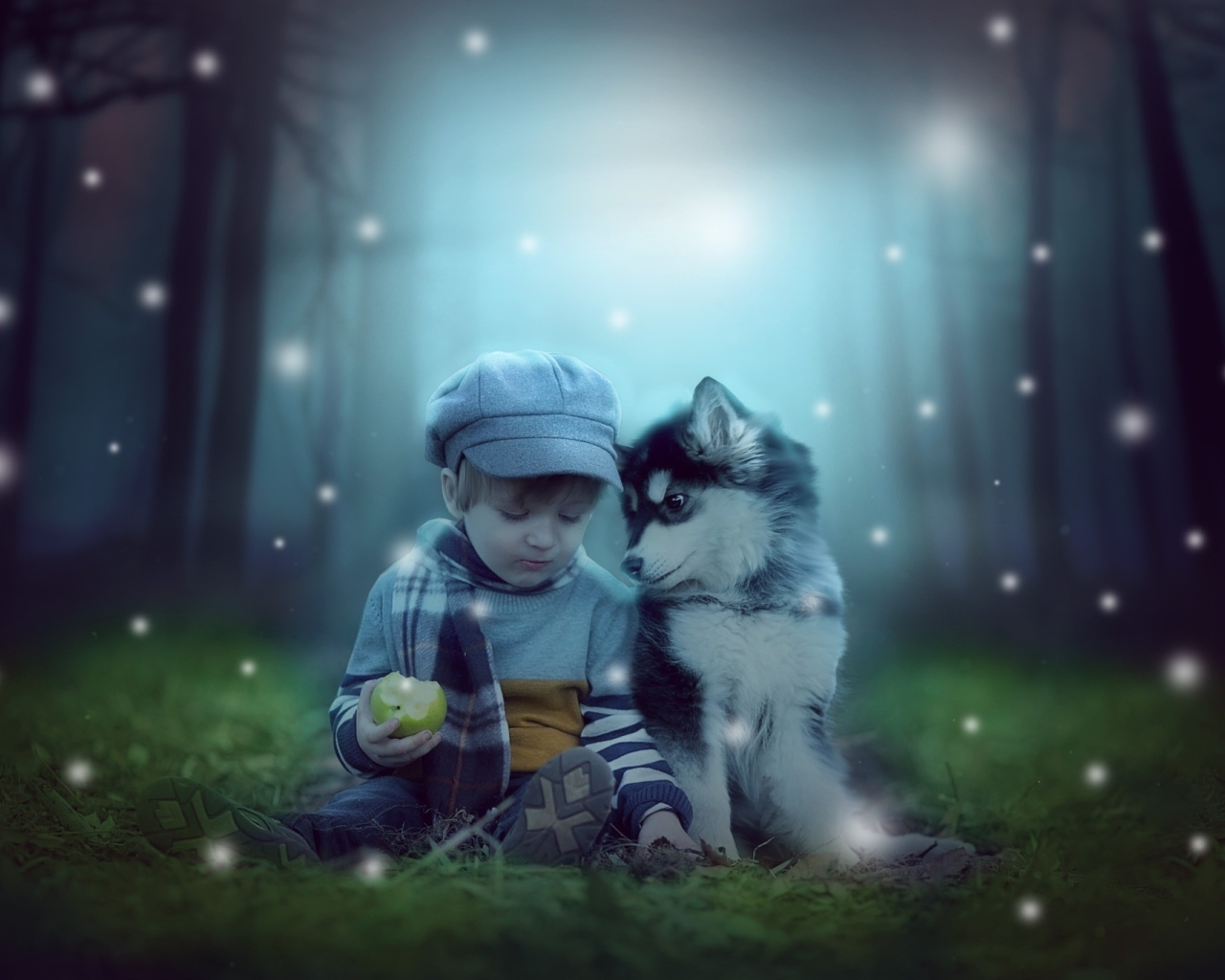 Маленький мальчик с щенком сидят на траве в лесу