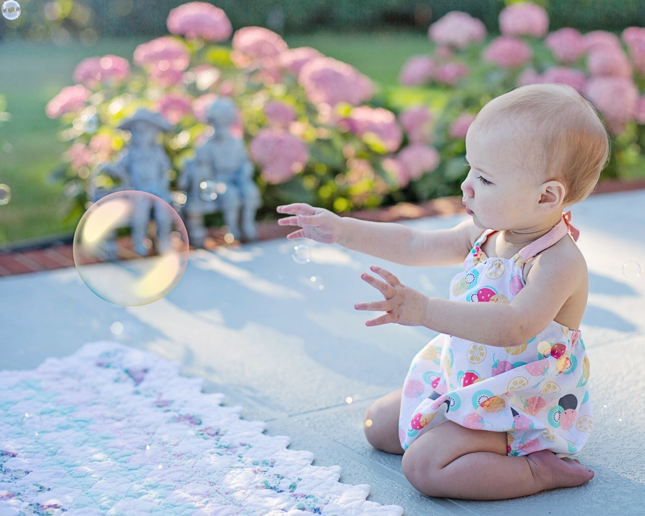 Маленькая девочка ловит мыльный пузырь