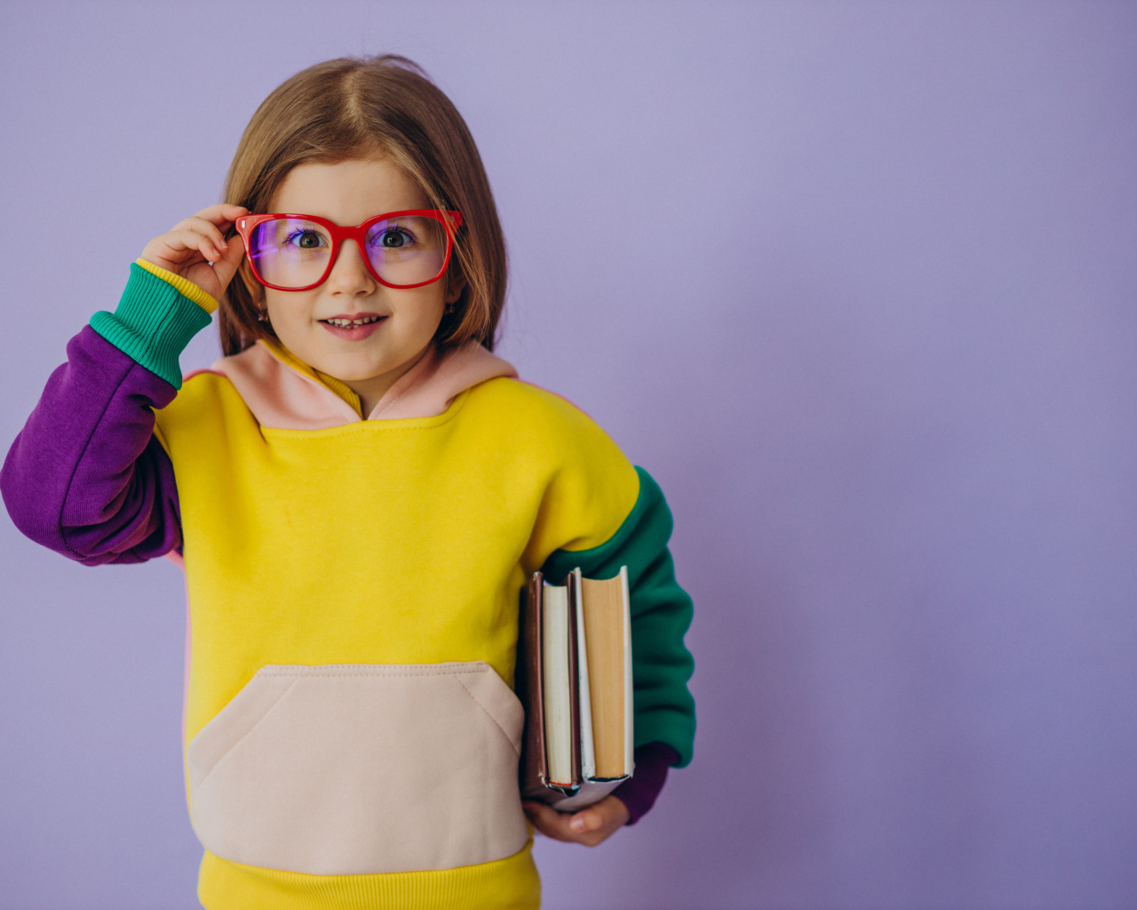 Маленькая девочка в очках с книгами в руке