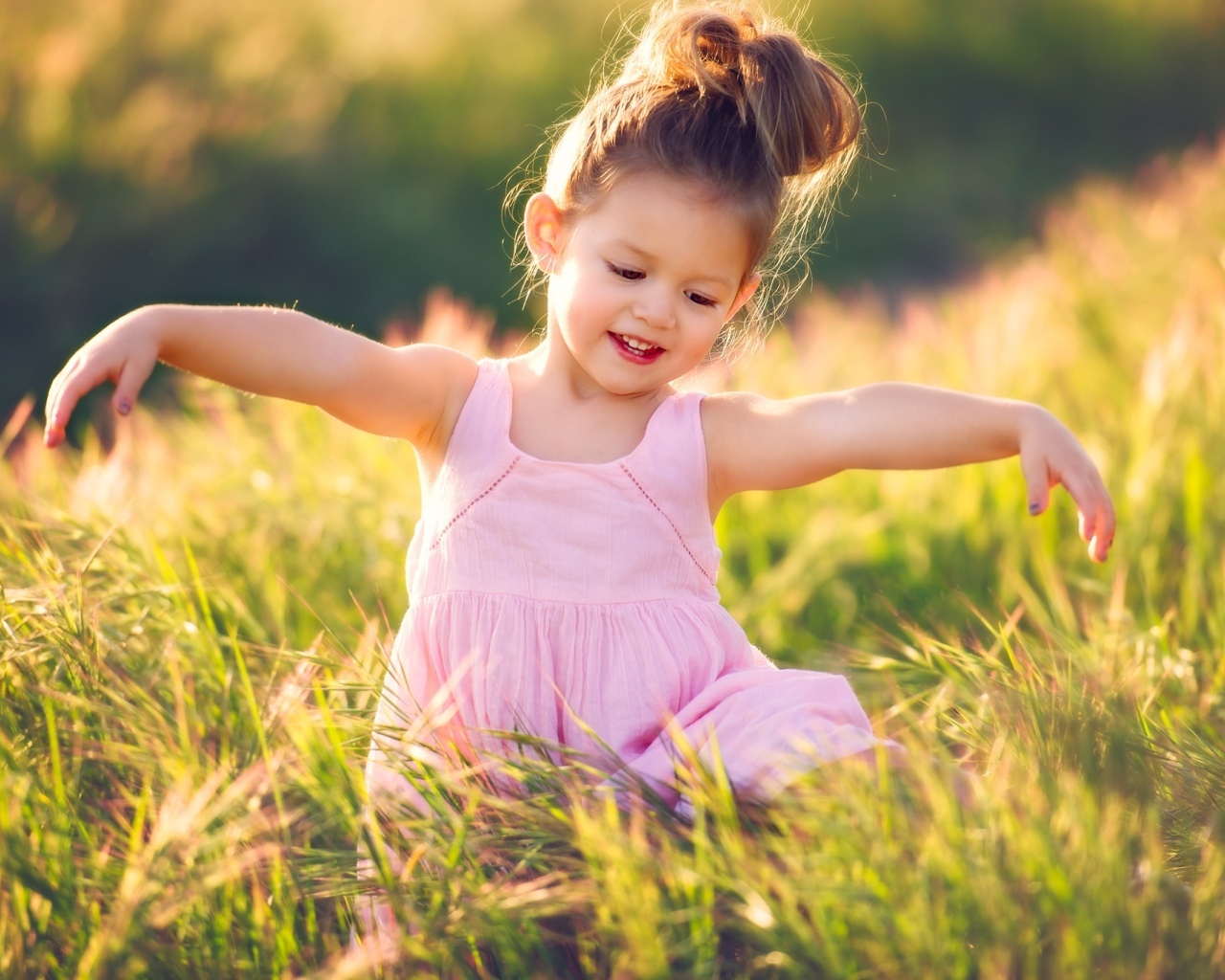 Маленькая девочка в розовом платье в зеленой траве